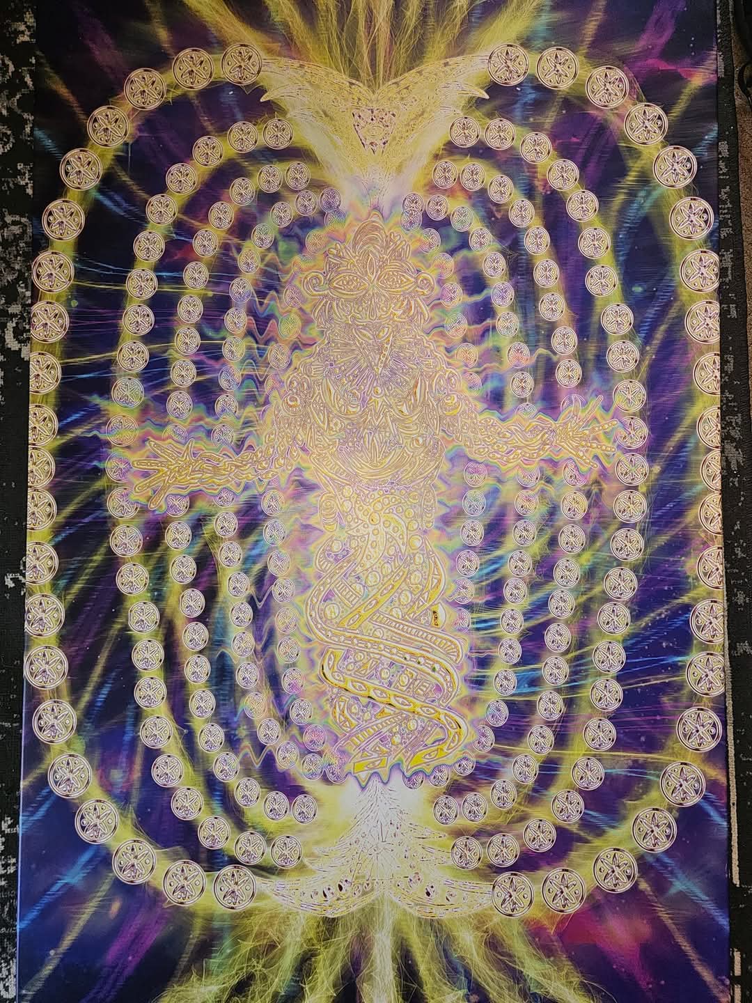 Digitised version of the same being, glowing in golds, violets and blues, encircled by concentric rings of mandala-like discs with bursts of radiant energy at the top and bottom.